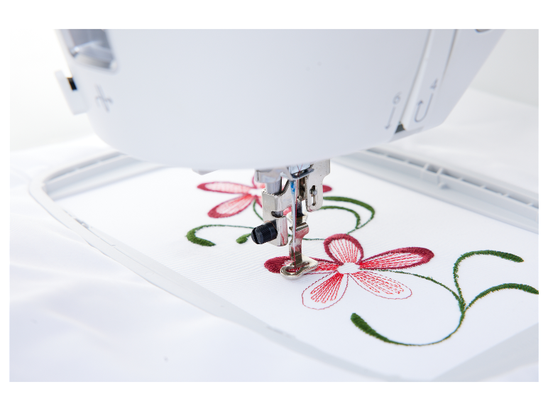 Vyšívací stroj vytváří červeno-zelený květinový vzor.