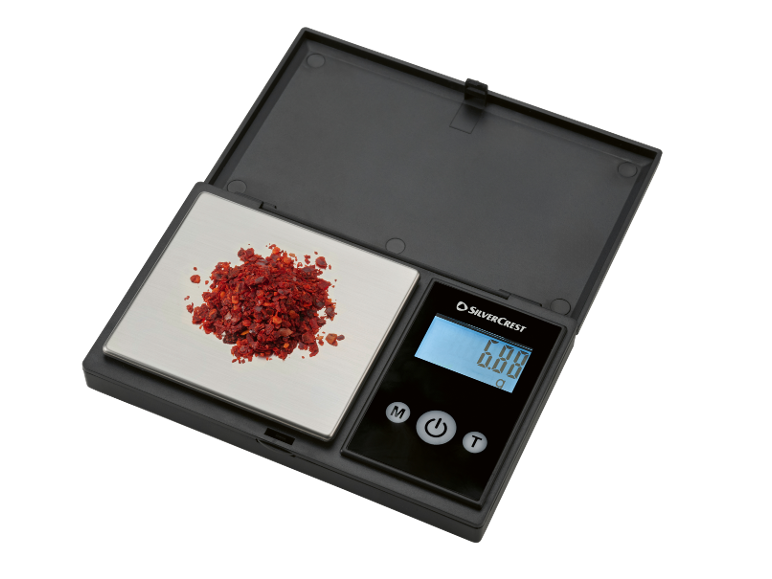 Digitální kuchyňská váha s červenými chilli vločkami, ukazuje 0,00 g.
