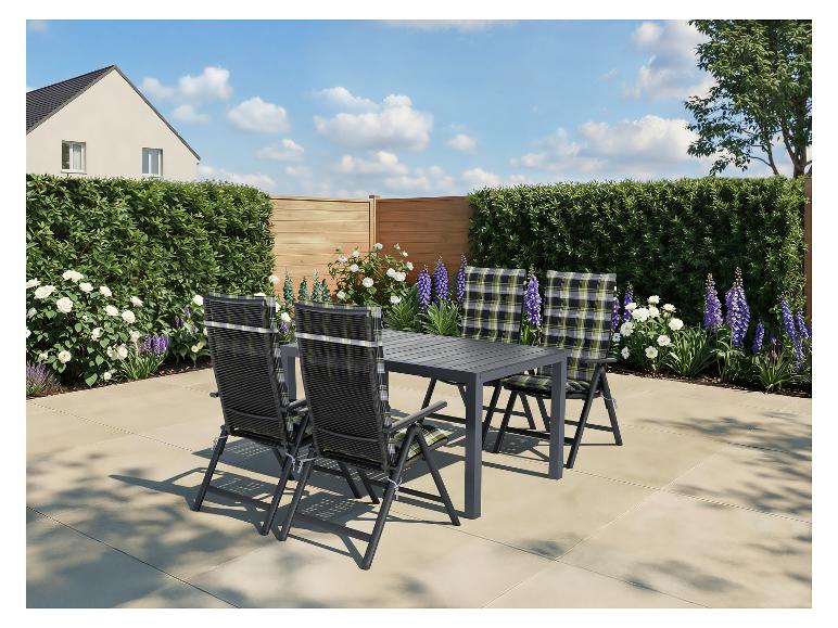 Zahradní jídelní set s šedým stolem a čtyřmi židlemi s kostkovanými polštáři na zahradě.