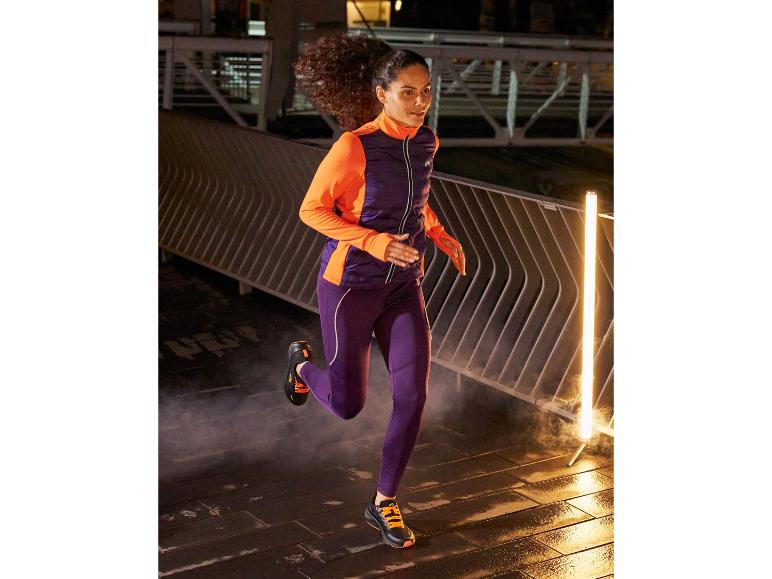 Žena v fialovém běžeckém oblečení a černých běžeckých botách běží v noci.