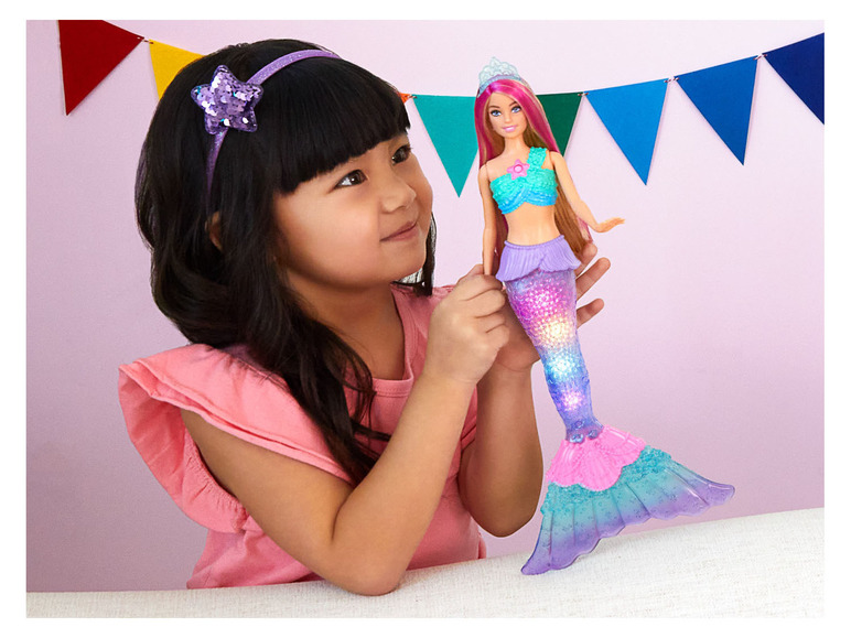 Dívka drží svítící panenku Barbie mořské panny.