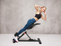 Žena ve sportovním oblečení cvičí na fitness lavičce.