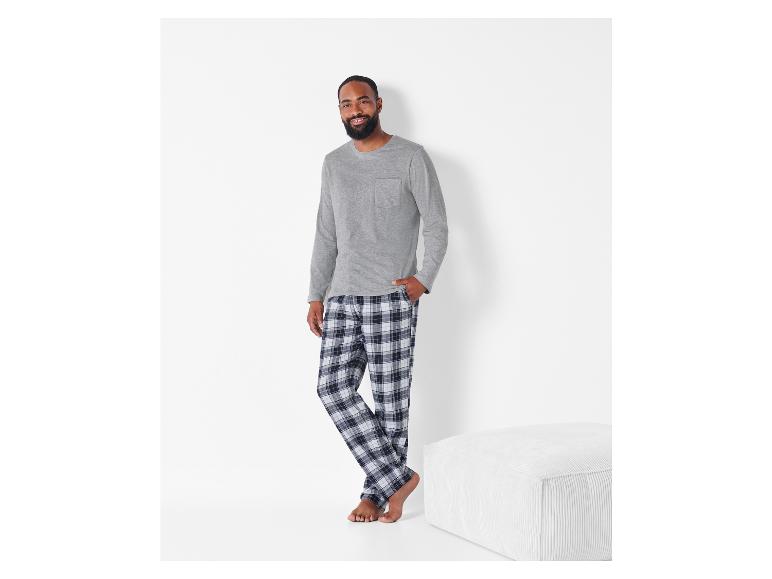 Muž v šedém tričku s dlouhým rukávem a kockovaných pyžamových kalhotách.