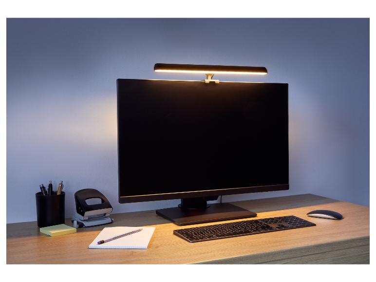 Počítačový monitor s lampou nad ním, klávesnice a myš na stole.