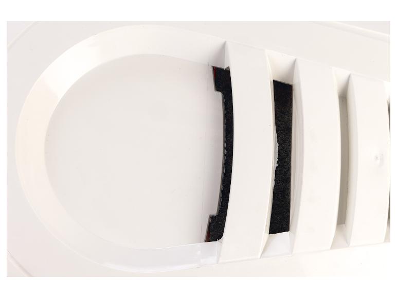 Detail bílé ventilační mřížky s tmavým filtračním materiálem viditelným za lamelami.
