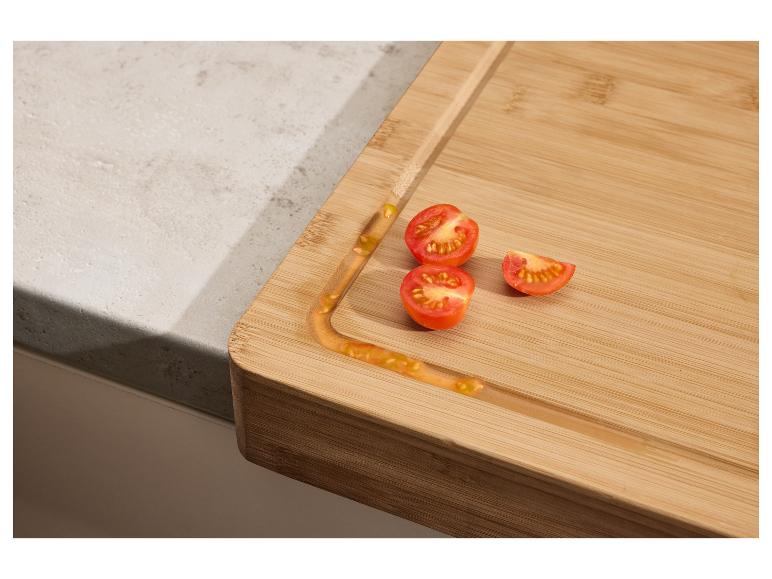 Bambusové prkénko s nakrájenými cherry rajčaty na kuchyňské lince.