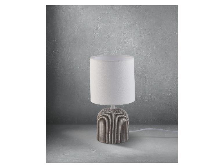 Moderní stolní lampa s bílým stínidlem a šedou keramickou základnou.