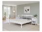 Ložnice s bílou postelí, nočními stolky a kobercem.