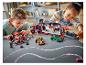 Dvě děti si hrají se sadami LEGO Speed Champions, včetně přepravního kamionu a závodních aut.