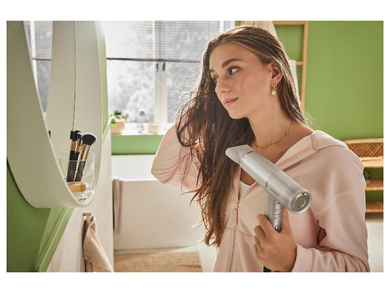 Žena suší vlasy fénem SensCare v koupelně.