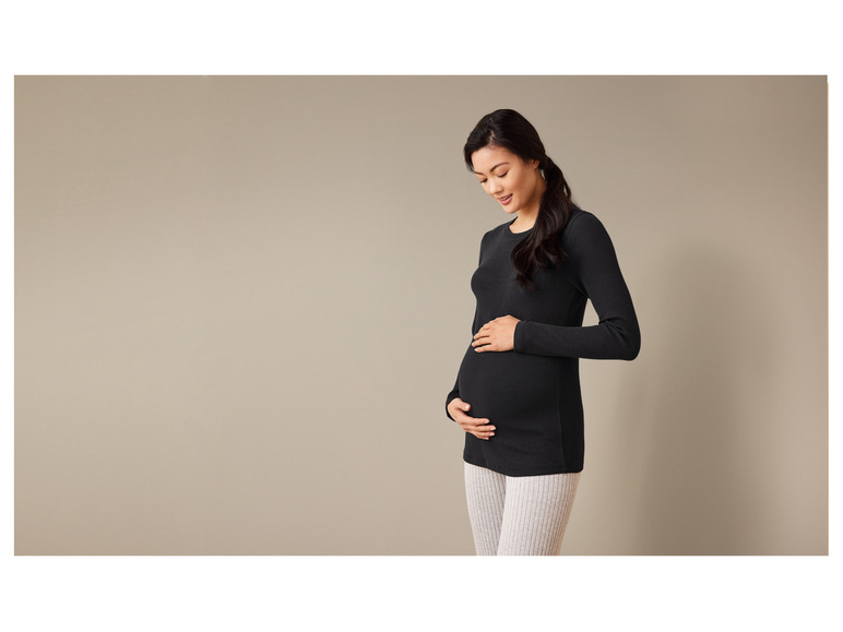 Těhotná žena v černém tričku a šedých legínách.