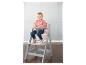 Dívka sedí na šedé vysoké židličce Stokke Tripp Trapp.