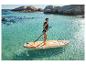 Žena v plavkách a záchranné vestě na paddleboardu v tyrkysové vodě se skalami v pozadí.