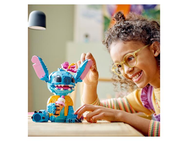 Usmívající se dítě si hraje s figurkou LEGO Stitch držící zmrzlinu.
