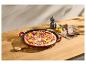 Pizza se salámem, červenou cibulí a paprikami v litinové pánvi na dřevěném stole.