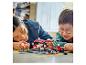 Dva lidé si hrají se sadou LEGO Speed Champions, závodním autem a pit stopem.