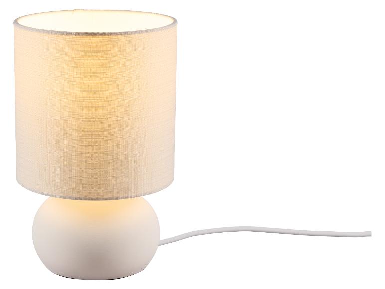 Bílá stolní lampa s válcovým látkovým stínidlem a kulatou základnou, s kabelem.