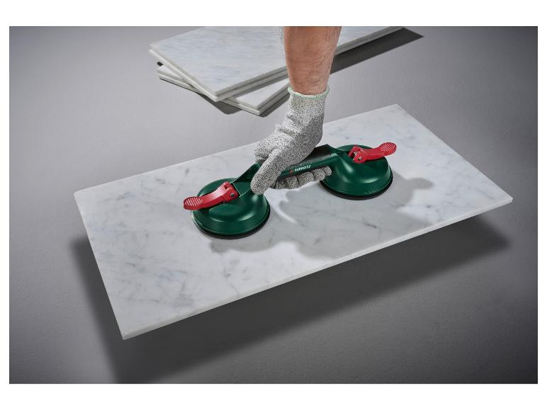 Osoba zvedá mramorovou dlaždici pomocí dvou přísavek Parkside.