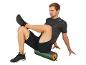 Muž ve sportovním oblečení sedící na pěnovém válci.