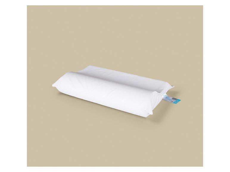 Bílý ortopedický polštář s modrou etiketou na béžovém pozadí.