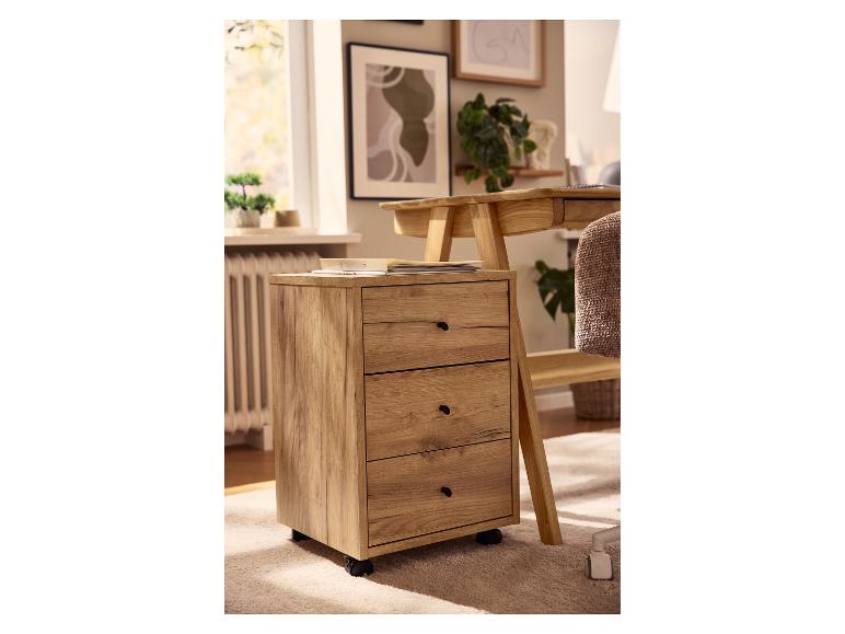 Dřevěný pojízdný kontejner se třemi zásuvkami vedle stolu v domácí kanceláři.