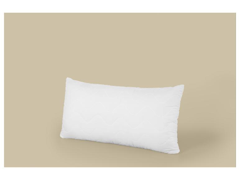Bílý obdélníkový polštář s vlnitým vzorem na béžovém pozadí