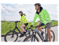 Dva cyklisti v cyklistickém oblečení Decathlon jedou na elektrokolech.
