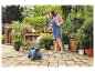 Žena zalévá květiny v květináčích zahradní hadicí Gardena.