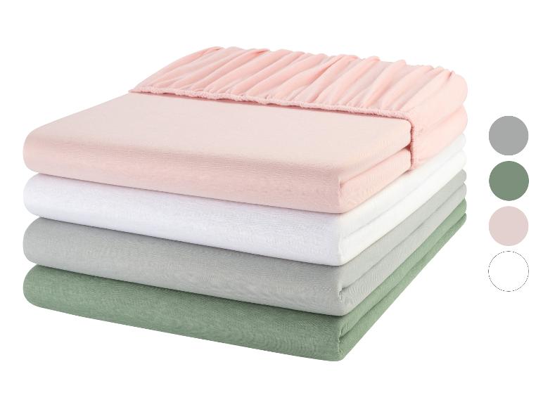 Hromádka růžových, bílých, šedých a zelených prostěradel.