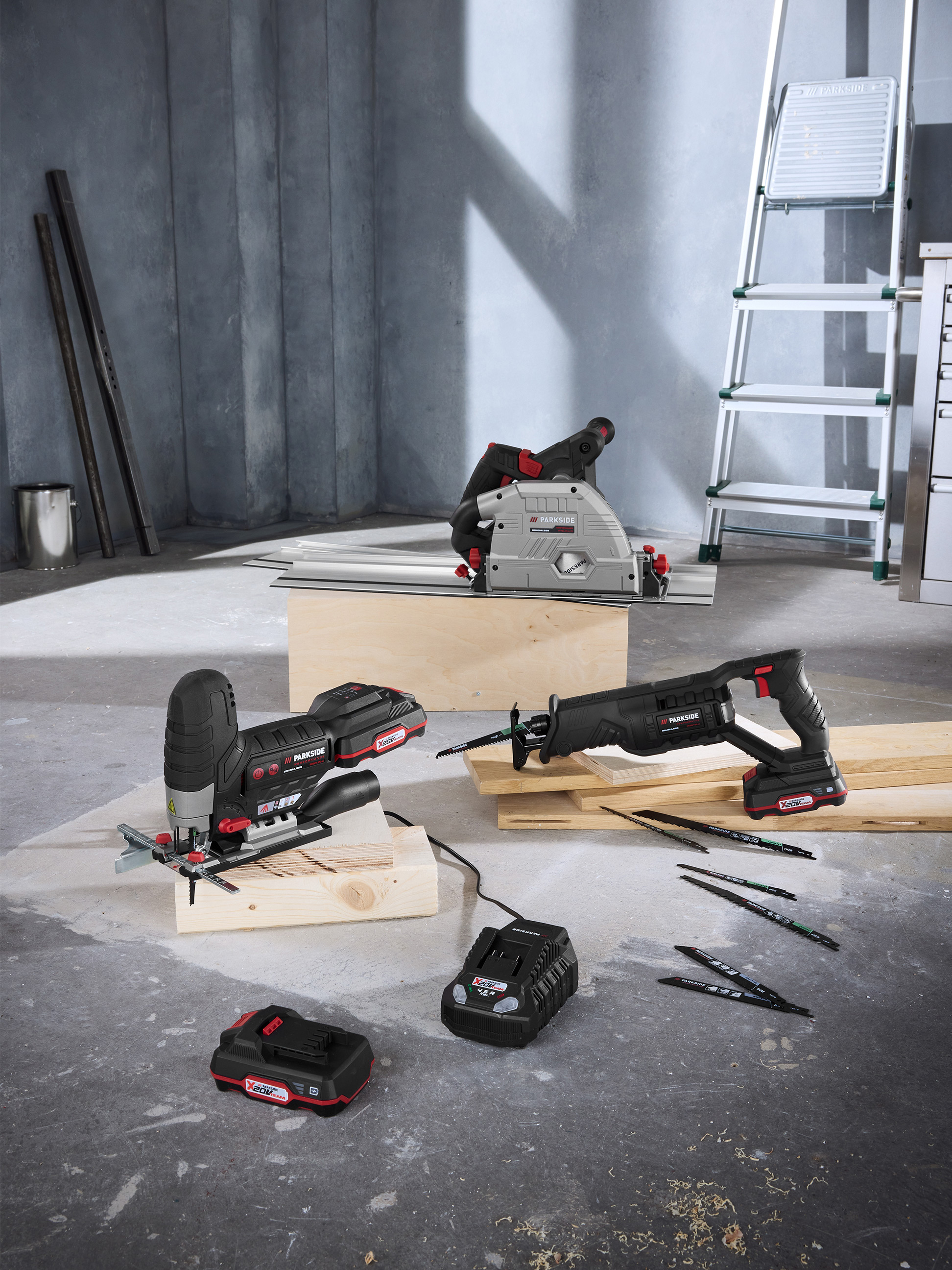 Elektrické nářadí Parkside: ponorná pila, přímočará pila a pila ocaska s bateriemi a příslušenstvím v dílně.