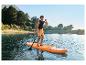 Muž pádluje na paddleboardu na jezeře obklopeném stromy a horami.