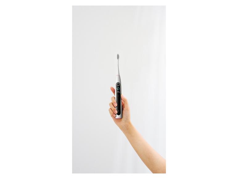 Ruka drží elektrický zubní kartáček