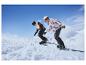 Dva lidé ve sjezdovém oblečení jedou na snowboardu po zasněženém svahu.