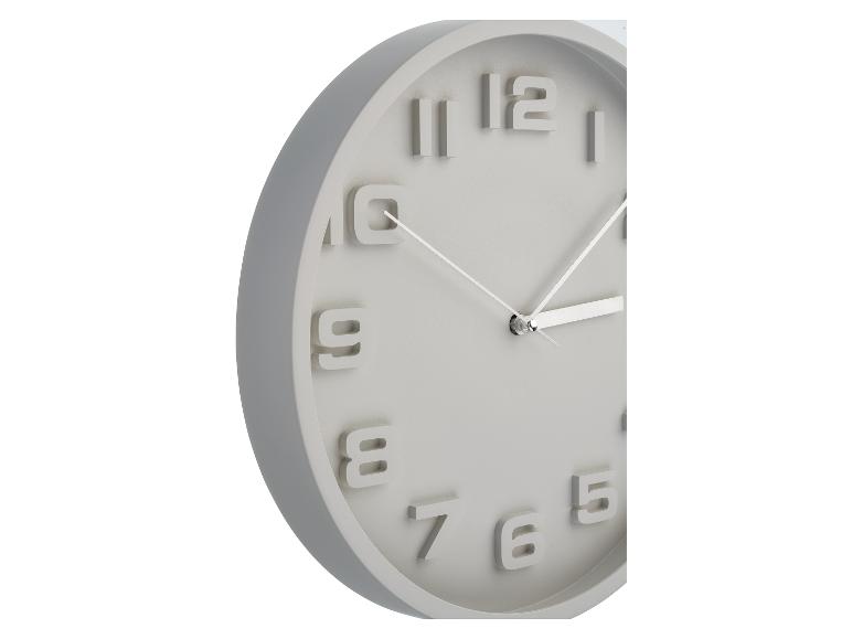 Kulaté šedé nástěnné hodiny s reliéfními číslicemi.