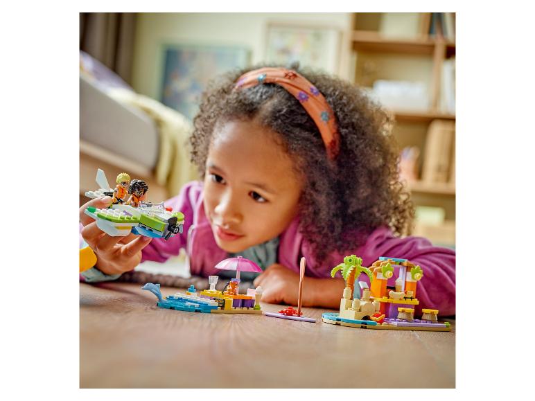 Dívka si hraje se stavebnicemi LEGO Friends na podlaze.