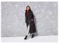 Žena v černém zimním kabátu, stříbrných kalhotách a černých botách.
