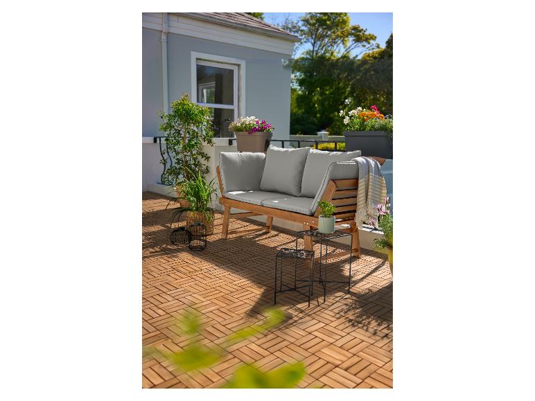 Dřevěná lavice s polštáři na terase s dřevěnou podlahou a květináči.