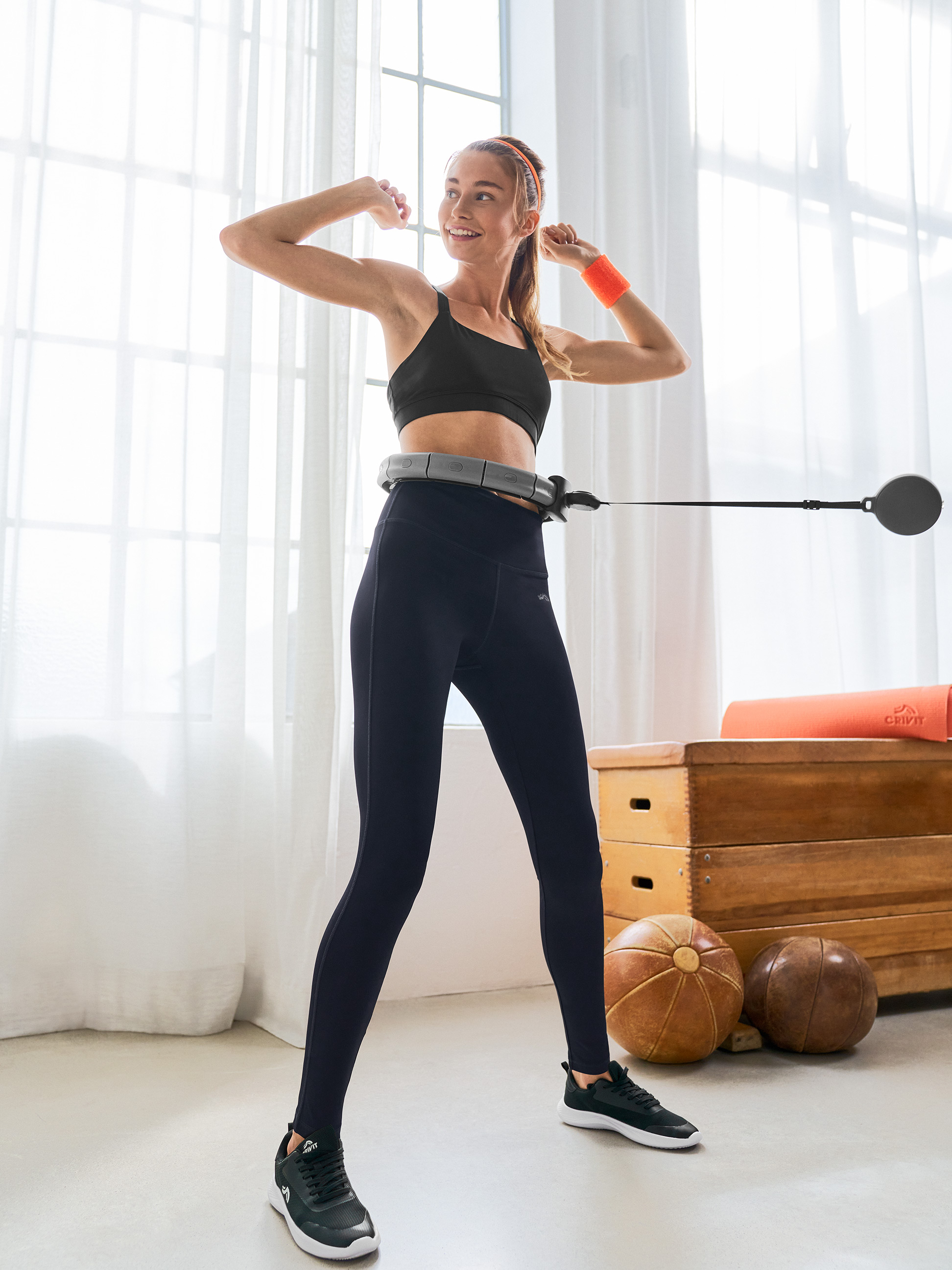 Žena v Crivit sportovní podprsence a legínách používající chytrý hula hoop