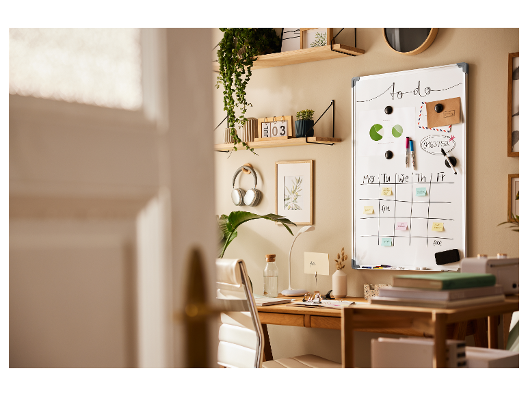 Bílá tabule, organizovaný stůl s rostlinami a sluchátky.