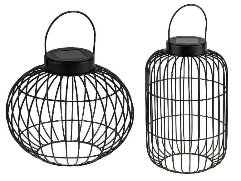 Dvě černé kovové dekorativní solární lucerny, jedna kulatá a jedna válcová.