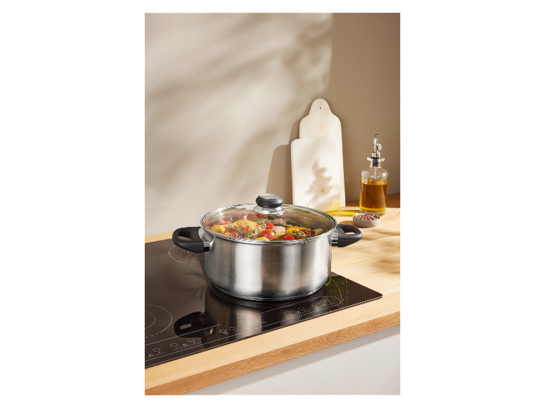 Nerezový hrnec se skleněnou pokličkou na indukční varné desce.