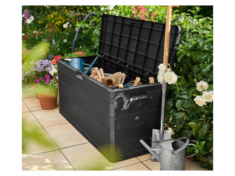 Černý zahradní úložný box Parkside plný nářadí, konev a lopata.