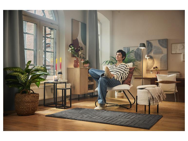 Osoba relaxuje v moderním a útulném obývacím pokoji na křesle.