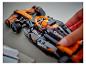 Ruka vkládá figurku do černo-oranžového závodního vozu LEGO McLaren.