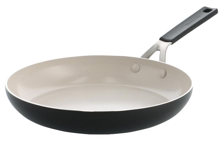 Pánev KitchenAid s krémovým vnitřkem a černým vnějškem, s kovovou a černou rukojetí.