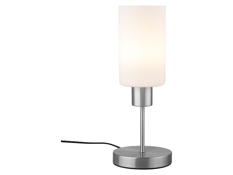 Moderní stolní lampa z matného skla a broušeného kovu.