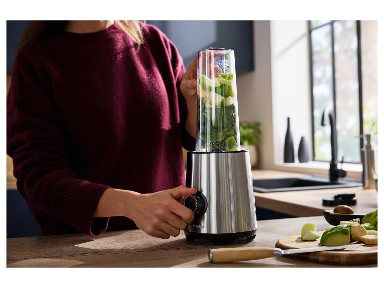 Žena používá mixér s ovocem a zeleninou na smoothie v kuchyni.