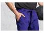 Muž ve fialových teplákách a s černým fitness míčem.