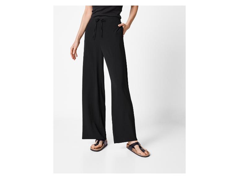 Žena v černých kalhotách a sandálech Birkenstock.