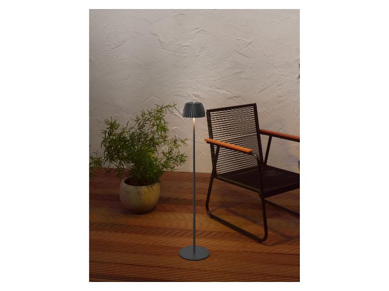 Moderní stojací lampa a rostlina v květináči na dřevěné terase s židlí.